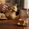 Brass_kettle_pouring_tea_cup_202607121033 Royal Handcrafted Pure Brass Tea Kettle (Teapot / Ketli) – Vintage Antique Finish with Intricate Peacock & Floral Engravings, Curved Handle & Dome Lid