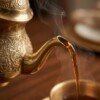 Hot_tea_flowing_from_spout_202607121033 Royal Handcrafted Pure Brass Tea Kettle (Teapot / Ketli) – Vintage Antique Finish with Intricate Peacock & Floral Engravings, Curved Handle & Dome Lid